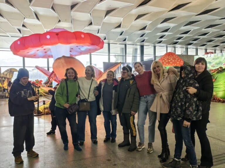 Група хора пред големи цветни буболечки в изложбена зала.